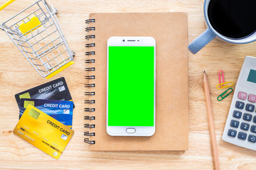 Credit cards,notebook,flower pot tree,smartphone,Shopping cart and coffee cup on wooden background,Online banking Concept,Top view office table.