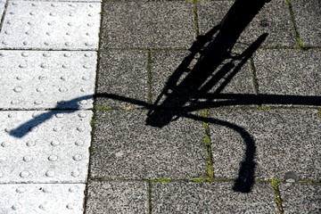 Schatten eines geparkten Fahrrads auf dem Gehsteig