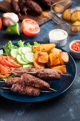 Grilled shish kebab served with fried potatoes
