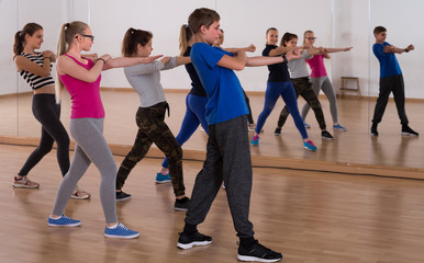 positive teenage boys and girls learning in dance hall