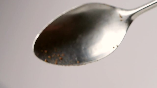 A full spoon of coffee. Coffee powder falling in slow motion from spoon