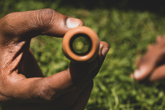 Hand holding a indian pot smoking pipe (chillum) to show the inside of the pipe