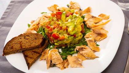 Salad guacamole with fresh tomatoes and arugula served with trout fillet