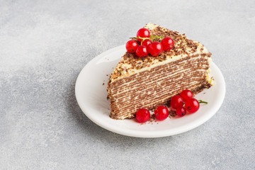 Cake of thin chocolate pancakes and pistachio cream with red currant berries.