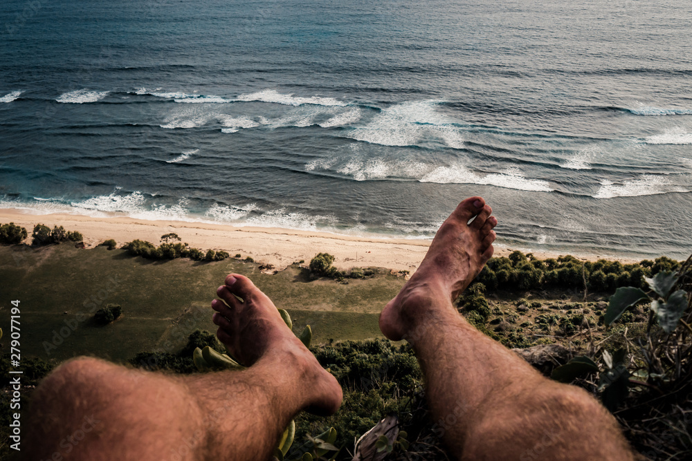 Wall mural pov view of legs on hill and ocean.