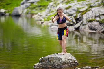 Woman kickbox fighter training by the lake