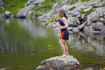 Woman kickbox fighter training by the lake