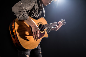 Guitarist, music. A young man plays an acoustic guitar on a black isolated background