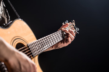 Guitarist, music. A young man plays an acoustic guitar on a black isolated background