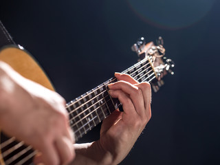 Guitarist, music. A young man plays an acoustic guitar on a black isolated background