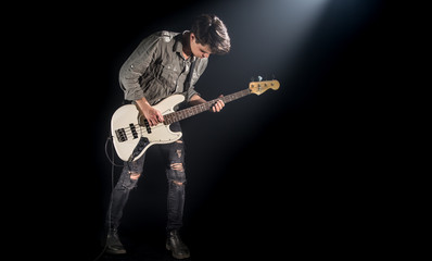the musician plays bass guitar, on a black background with a beam of light