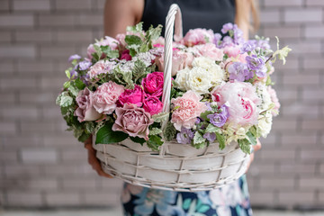 Flower arrangement in Wicker basket. Beautiful bouquet of mixed flowers in woman hand. Floral shop...