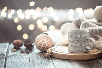 Fototapeta na wymiar Coffee cup over Christmas lights bokeh in home on wooden table with sweater on a background and decorations. Holiday decoration, magic Christmas