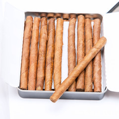 Box of cigarillos on a white background. On the box is one cigarillo. Selective focus