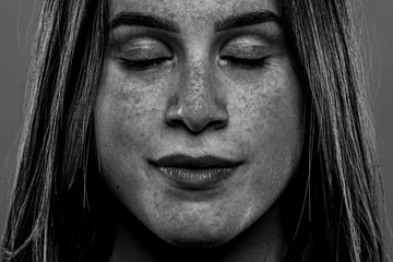 A closeup and monochrome view on the face of a twenty something Caucasian girl. UV light shows liver spots and damaged skin from not using sun protection.