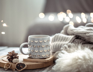 Obraz na płótnie Canvas Coffee cup over Christmas lights bokeh in home on wooden table with sweater on a background and decorations. Holiday decoration, magic Christmas