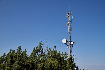 Cell tower at the top of the mountain among the greenery on a summer day