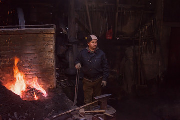 young traditional Blacksmith working with open fire