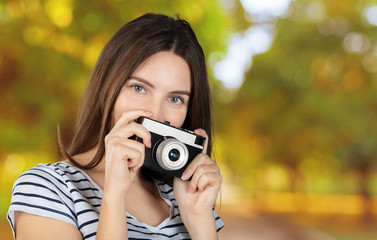 Portrait of a young smiling woman filming with retro camera isolated