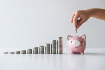 Hand putting coin into piggy bank for planning step up growing and savings