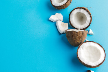 Slices of broken tropical coconuts on blue background. Top view
