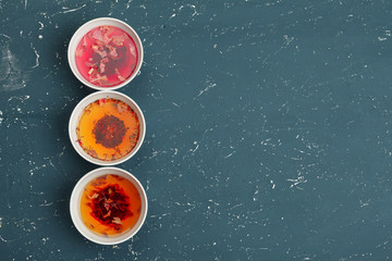 Tea concept. Different kinds of dry tea in ceramic bowls and cups of aromatic tea