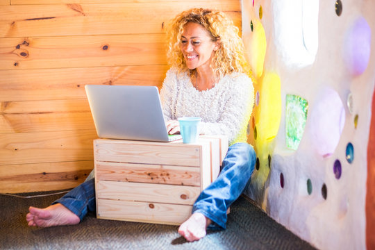 Cheerful worker people at home - blonde curly young woman smile and wotk on personal laptop computer sitting on the floor - freelance and writer profession for freedom office lifestyle