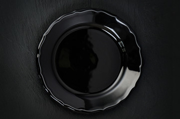 Empty rustic black plate on dark stone background, copy space, top view