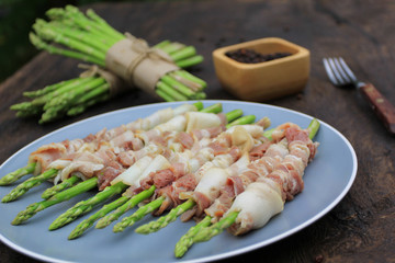Raw bacon wrapped green asparagus on wooden dark background