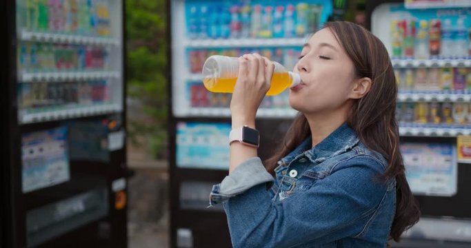Woman drink a bottle of juice at vending machine