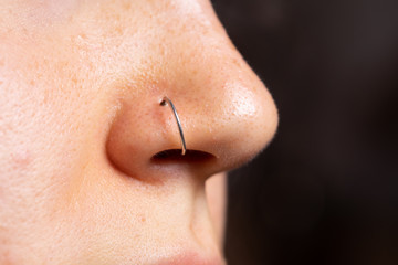 A closeup and side view on the small nose of a young Caucasian woman in her early twenties with a pierced nose. Open pores and blackheads can be seen with copy space on the right. - obrazy, fototapety, plakaty