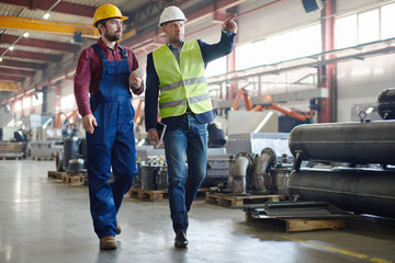 Engineers in hard hats working at the industrial plant.