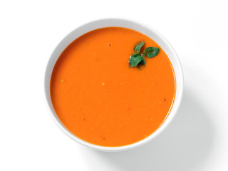 Traditional homemade tomato soup with basil leaf top view on a white background