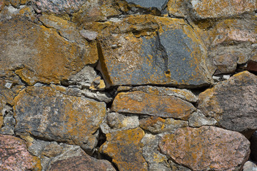 The texture of the old yellow stone wall of large cobblestones