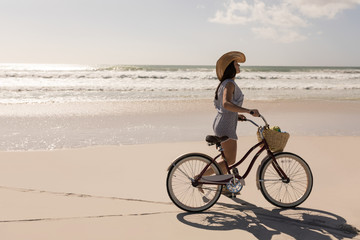 Fototapeta na wymiar Beautiful young woman with bicycle walking on beach