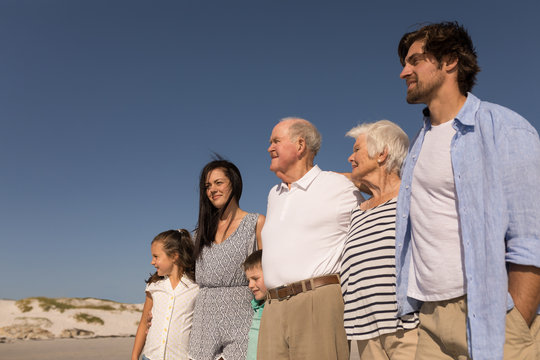 Family with arms around standing on beach