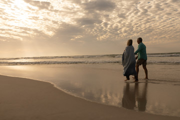 Senior couple walking hand in hand on the beach