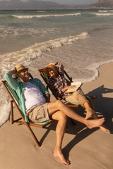 Senior couple having fun while relaxing on sun lounger at beach