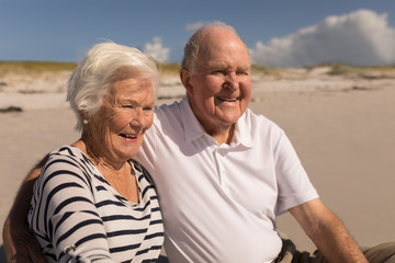 Happy senior couple sitting on beach