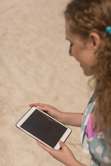 Young Caucasian woman using digital tablet at beach