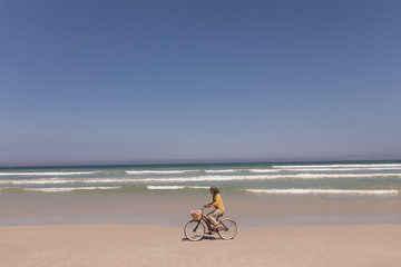 Senior woman riding bicycle on beach