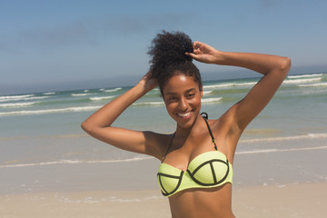 Young African American woman in green bikini and hands in hair looking at camera