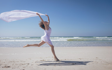 Happy woman holding scarf at beach