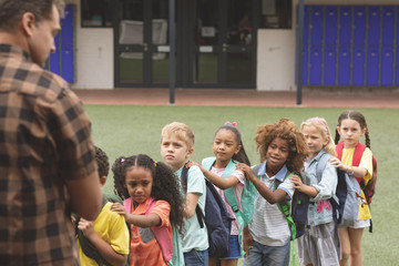School kids standing in a queue in the schoolyard 