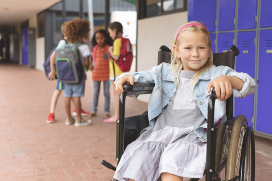 Schoolgirl sitting on wheelchair in corridor 