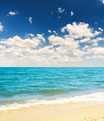 yellow sand beach and blue sea with clouds in sky