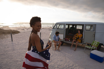 Mixed-race woman holding an American flag against his friends in background