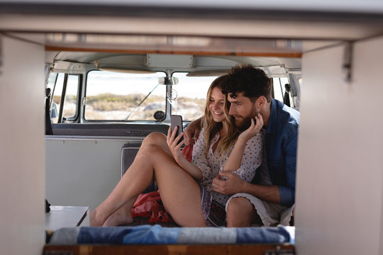Front view of couple taking selfie in camper van at beach