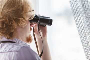 Man with binoculars spying on neighbors