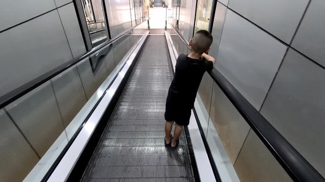 Asian boys on the escalator is moving down.